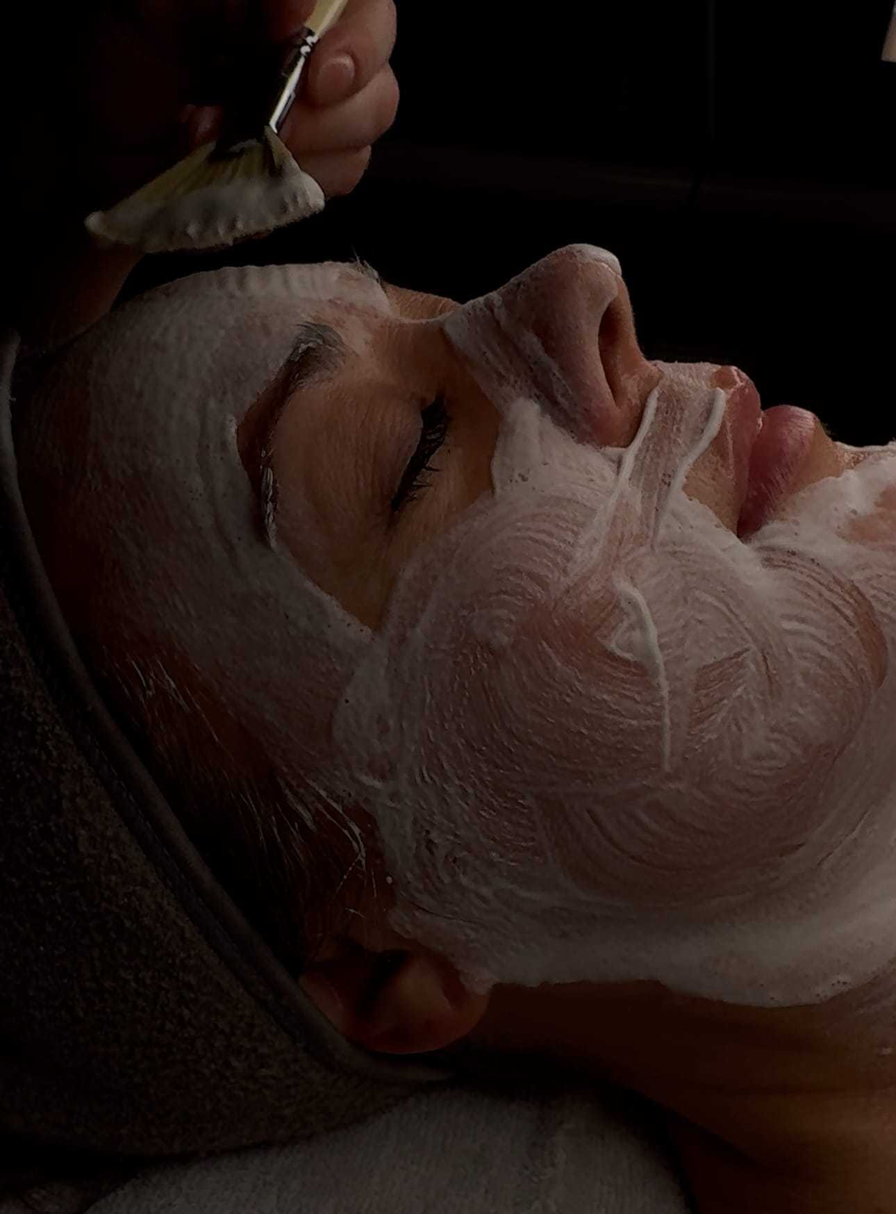 Facial treatment application with brush on woman's face.