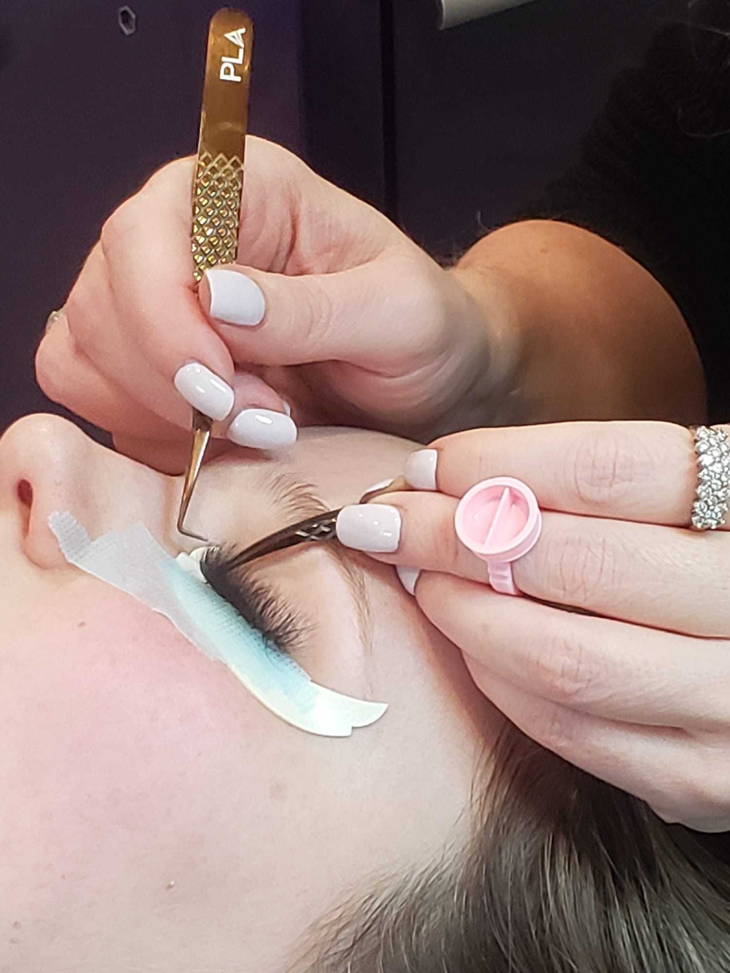 Close-up of a person receiving professional eyelash extensions applied by a technician.